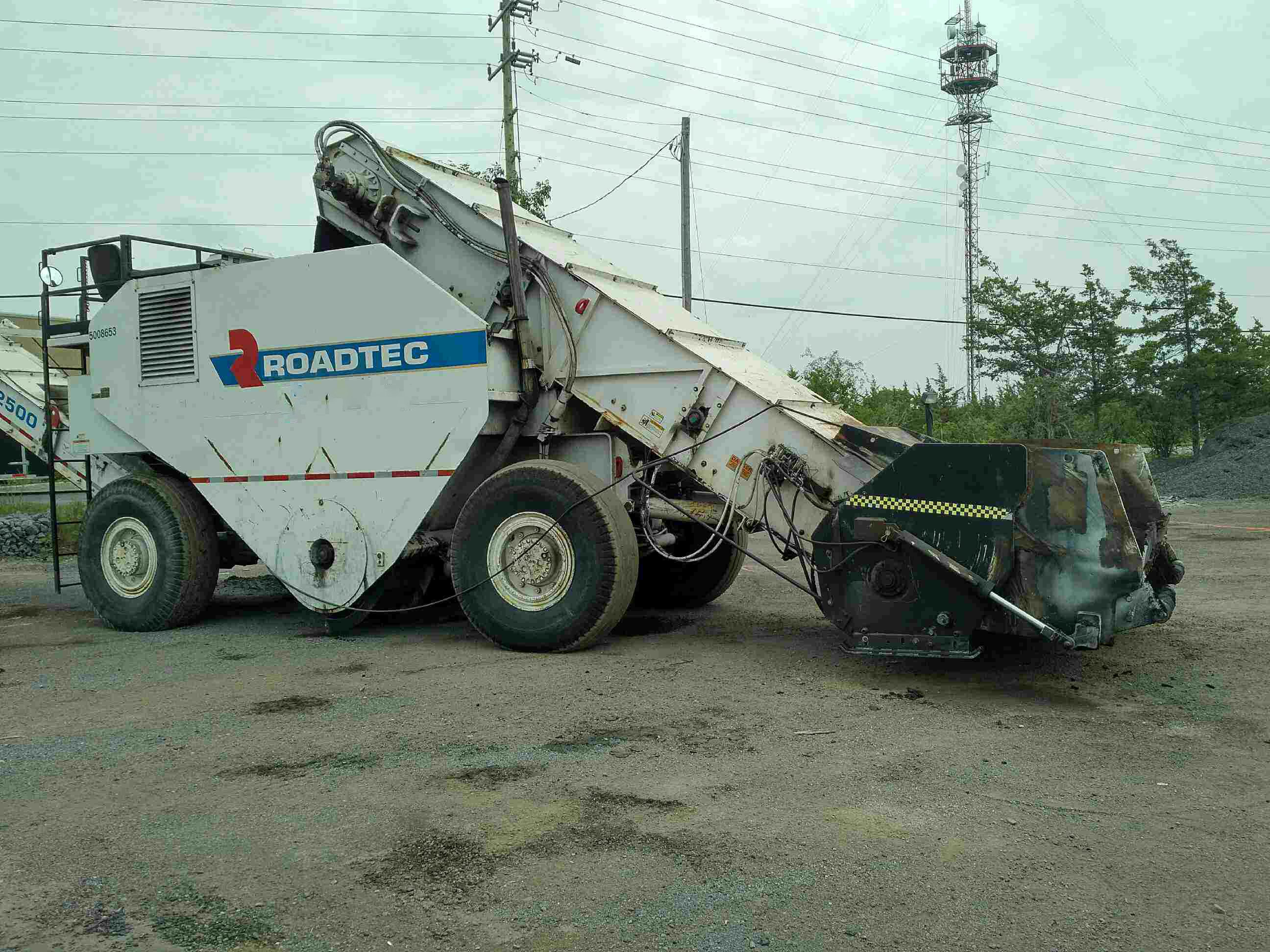 Asphaltfräse (Kaltfräse) von ROADTEC, auf einem Bauhof stehend, mit nach oben gerichtetem Förderband soll mittels Trockeneisstrahlen vom Asphalt gereinigt werden.