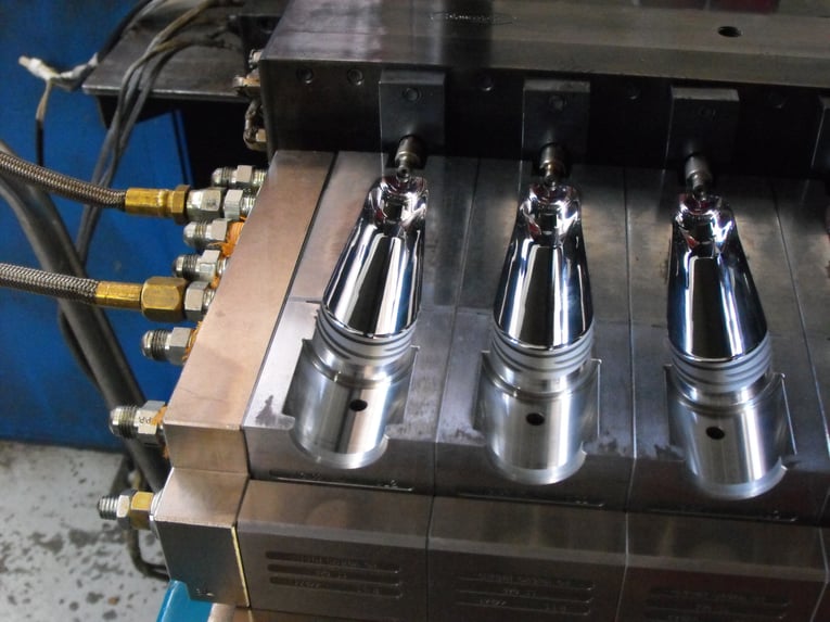 Nahaufnahme einer geöffneten Spritzgießform mit drei Kavitäten bei Silgan Plastics, die für die wartungsfreie Produktion mittels Cold Jet Trockeneisstrahlen vorbereitet wurde